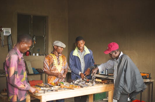 Group of men collaborating in a Ugandan workshop surrounded by tools and equipment.