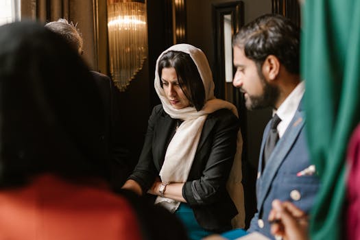 Group of professionals in a serious discussion indoors, showcasing diverse cultural attire.
